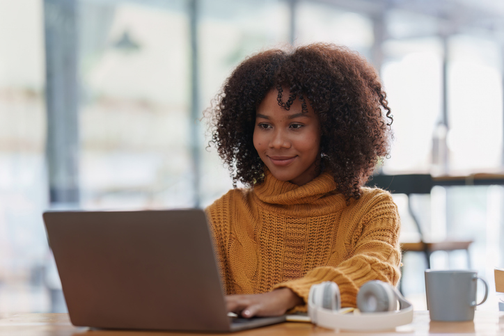 Young black African woman university student learning online using laptop computer. Smiling girl watch webinar or virtual education.